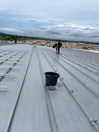 Worker installing metal roofing on a construction project
